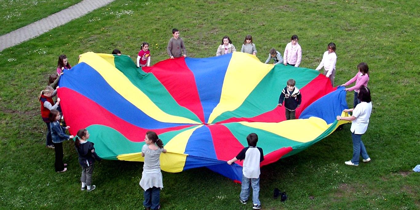 Kinder spielen mit Fallschirm